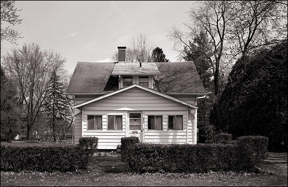 Black and white photograph of a white house in harsh sunlight. The film was given a shorter developing time to reduce contrast.