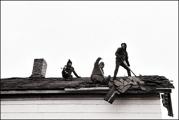 Roofers removing old shingles from a house.