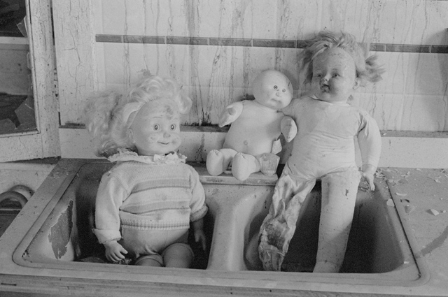 An un-edited scan of a black and white negative scanned with a Nikon LS-8000ED scanner using Vuescan software. Photograph of old dolls in an abandoned house.